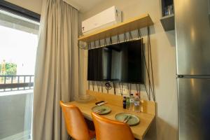 uma cozinha com uma mesa com cadeiras e uma televisão em Studio Novo perto do Allianz Parque em São Paulo