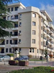 Un gran edificio con coches aparcados delante. en Aura apartman, en Čačak