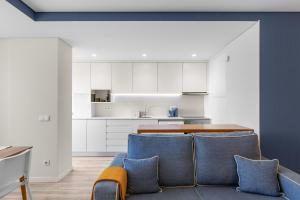 a kitchen with white cabinets and a blue couch at Casa da Praia - Matosinhos Mar in Matosinhos