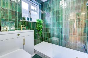 een groene betegelde badkamer met een bad en een wastafel bij Cottage in the centre in Colchester +17 foto's