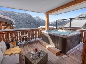 a hot tub on a deck with a view of mountains at L'O Rouge - Apt A02 - BO Immobilier- remises sur les forfaits de skis Châtel ou Portes du soleil in Châtel