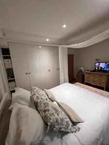 a bedroom with a large white bed and a television at Ensuite in London