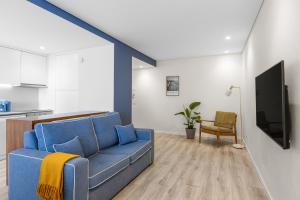 a living room with a blue couch and a tv at Casa da Praia - Matosinhos Mar in Matosinhos