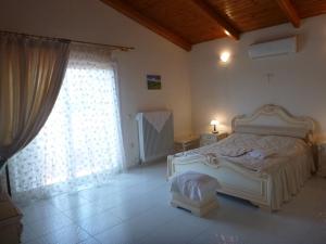 a bedroom with a white bed and a window at Villa Faidra in Eretria