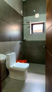 a bathroom with a toilet and a shower with a window at Vipinam, The riverside retreat in Kotamangalam