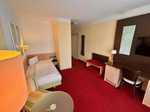 a hotel room with a bed and a desk at Hotel Phönix in Bad Füssing +2 photos