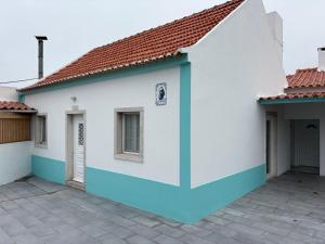 une maison blanche et bleue avec un toit de tuiles dans l'établissement Casa das Orquídeas Meco, à Sesimbra