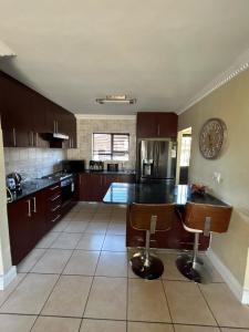 een keuken met bruine kasten en een klok aan de muur bij Holiday Home in Cape Town
