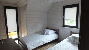 a bedroom with two beds in a room with two windows at Cztery Pory Roku - kominek, sauna, jacuzzi in Zarzecze +40 photos