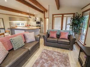 a living room with two couches and a kitchen at Oak Lodge in Rugeley