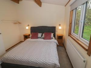 a bedroom with a large bed with two windows at Oak Lodge in Rugeley