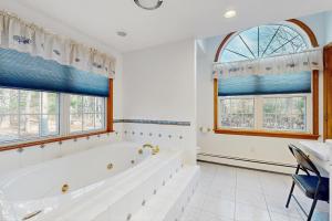 un bagno bianco con vasca e 2 finestre di Sandbar Hideaway a Old Silver Beach Altre 56 foto