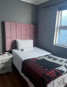 una camera da letto con un letto grande con testiera rosa di Station Home a Città del Capo