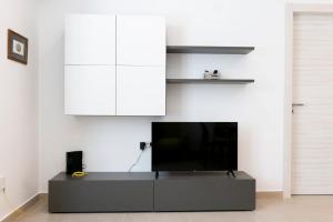 una TV a schermo piatto posizionata sopra un centro di intrattenimento di Marusu Apartments a Terrasini