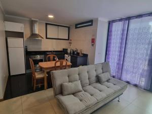 Una sala de estar con un sofá y una cocina. en Apto Vista Baía Machico, en Machico