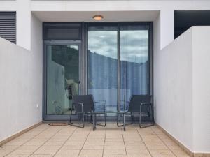 two chairs and a table on a balcony with sliding glass doors at Apto Vista Baía Machico in Machico +8 photos