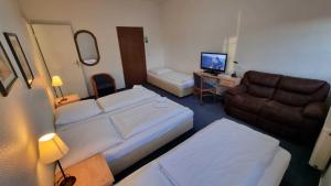 a hotel room with two beds and a couch at Hotel 3H Mannheim in Mannheim