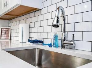 a stainless steel sink in a kitchen with white tiles at Jungle House Luxury Homes - Columbus Downtown Short North - Near Convention Center & Nationwide Arena - Free Parking - Pet Friendly - Over 5,800 Five Stars in Columbus
