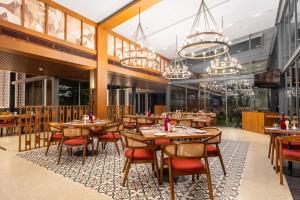 a restaurant with wooden tables and chairs and chandeliers at Wyndham Garden Jim Corbett Chhoi in Belparāo