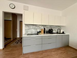 Una cocina con gabinetes blancos y un reloj en la pared. en Modlinska Residence by JumpInHere, en Nowy Dwór Mazowiecki