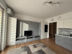 Una cocina con gabinetes blancos y un televisor de pantalla plana. en Modlinska Residence by JumpInHere, en Nowy Dwór Mazowiecki 3 fotos más