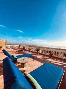 a patio with blue pillows and a table and the beach at The Bay House Essaouira in Essaouira