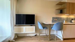 a kitchen with two chairs and a table with a television at Écume et Sérénité Parking Privé Wifi Clim et LIT en 140 in La Grande-Motte +22 photos