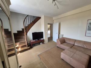 ein Wohnzimmer mit einer Couch und einer Treppe in der Unterkunft Maison de Vacances Chez La Prade in Salagnac