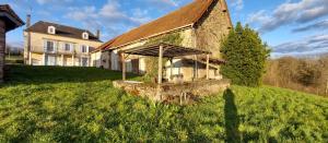 ein altes Haus auf einem grasbewachsenen Hügel mit einem Baum in der Unterkunft Maison de Vacances Chez La Prade in Salagnac