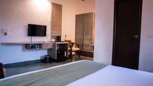 Trisara Boutique Stay في ميسور: غرفة فندق مع سرير وتلفزيون