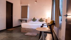 Trisara Boutique Stay في ميسور: غرفة نوم بها سرير وكرسي في الغرفة