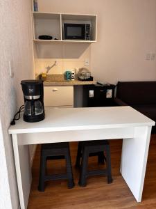 a white table with a coffee maker and a microwave at 100 metros da praia do forte in Cabo Frio