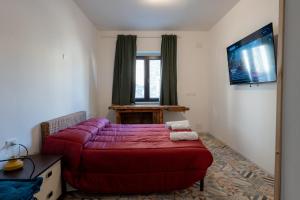 - une chambre avec un lit rouge et une télévision à écran plat dans l'établissement FIAMBI & b, à Colugna