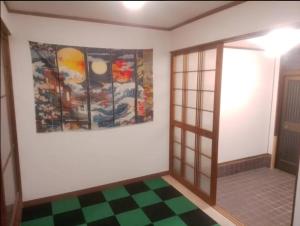 a room with a painting on the wall and a checkered floor at ふるさと in Wada