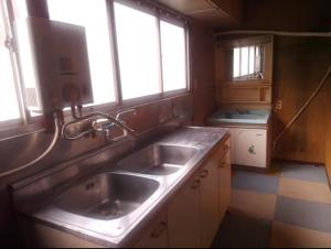 a kitchen with a sink and two windows at ふるさと in Wada