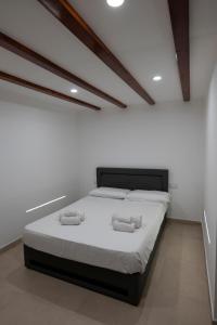 una camera da letto bianca con un letto con due asciugamani sopra di Marusu Apartments a Terrasini