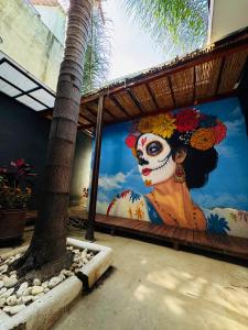 een schilderij van een vrouw met een suikerschedel op een muur bij Leveli Coliving & Hostel Oaxaca in Oaxaca City