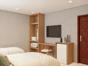 ein Schlafzimmer mit einem Bett und einem Fernseher an der Wand in der Unterkunft Villa Sol e Mar in Maragogi