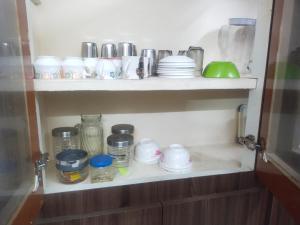 a shelf with cups and dishes on it at Good stay Nungambakkam in Chennai +10 photos