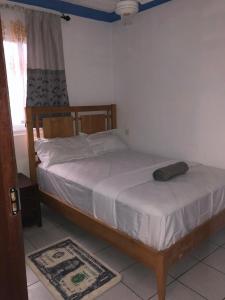 a bedroom with a wooden bed with white sheets at Blue Waves Apartments in Mombasa
