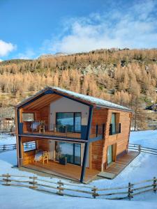 a log house with a deck in the snow at Les Chalets de Pierrot in Cogne