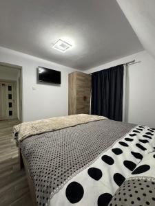 una camera da letto con un letto con un piumone bianco e nero di Sunny Hill Cab a Bulz Altre 8 foto