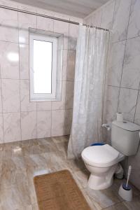 a white bathroom with a toilet and a window at Cazare-LaBadeaMircea in Soroca +5 photos
