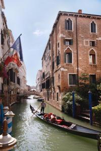 a man is paddling a gondola down a canal at Hotel Donà Palace in Venice