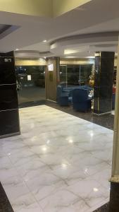 a lobby with a white tile floor and blue chairs at فندق اجنحة السمو إن in Aḩad al Masāriḩah