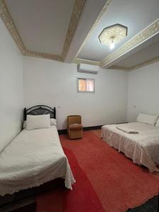 1 dormitorio con 2 camas y alfombra roja en Palms Magraman, en Skoura 6 fotos más