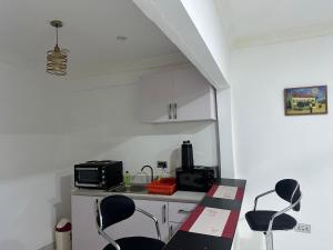 a kitchen with two chairs and a counter with a microwave at Akwaaba BnB in Accra