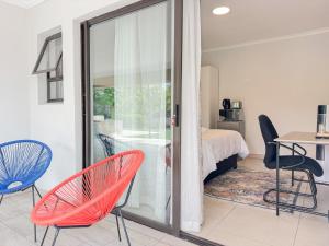 a room with a bed and two chairs and a table at Berrybliss Guesthouse - Sandton in Sandton