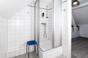 a shower with a blue stool in a bathroom at Pension zur Schleuse Kleinmachnow in Kleinmachnow