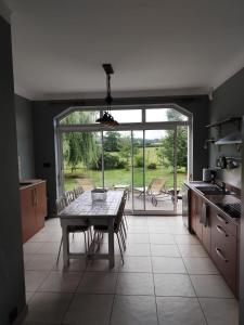a kitchen with a table with chairs and a large window at Gite du bout là haut in Audincthum